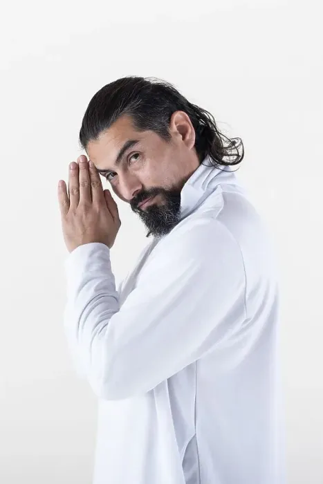 Framed Print : A man dressed in white clasping hands while looking at camera over white background