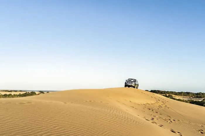 Framed Print : A man driving a 4x4 vehicle in a dune at sunset