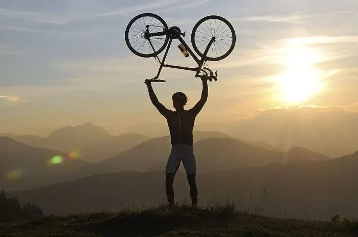 Framed Print : Man holding a racing bike above his head into the air