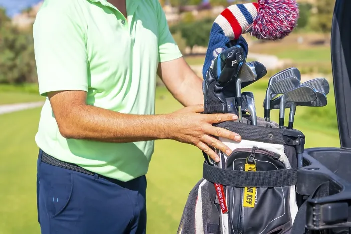 Framed Print : Man playing golf, picking up the bag of clubs and placing it in the buggy Framed Print : Man playing golf, picking up the bag of clubs and placing it in the buggy