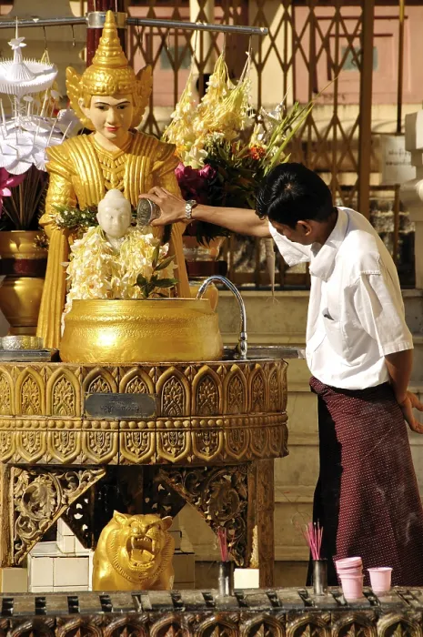 Framed Print : Man pouring water over a Buddha statue