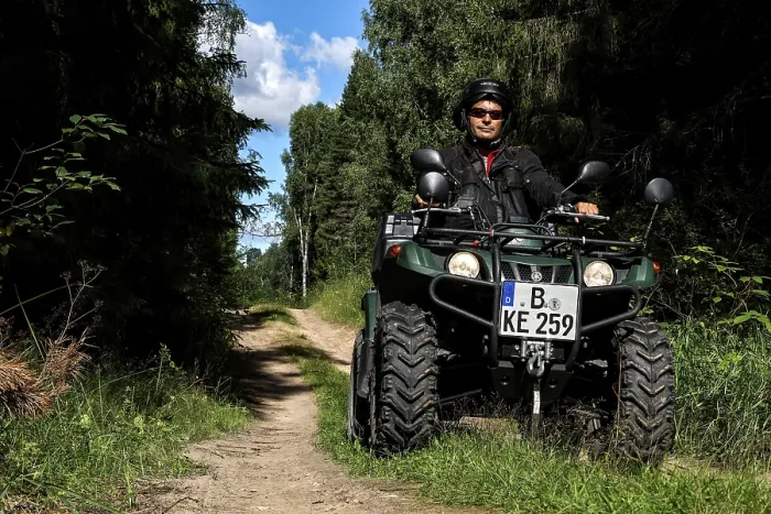 Framed Print : Man rides ATV on a forest trail surrounded by tall vegetation