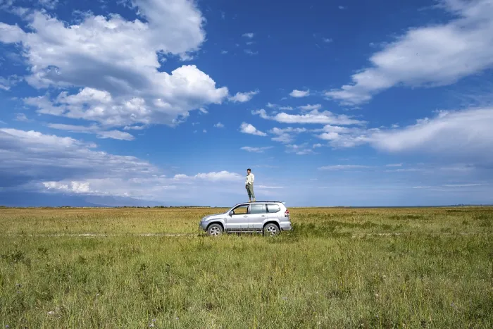 Framed Print : A man stands on a car in the centre of a vast landscape under a blue sky