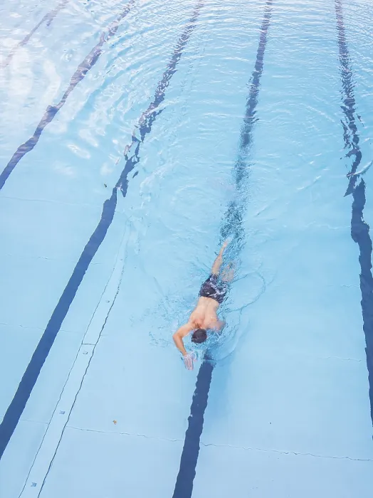 Framed Print : A man swims in the clear blue water of a pool along the lanes