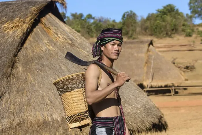 Framed Print : Man in traditional costume in front of a Phnong house