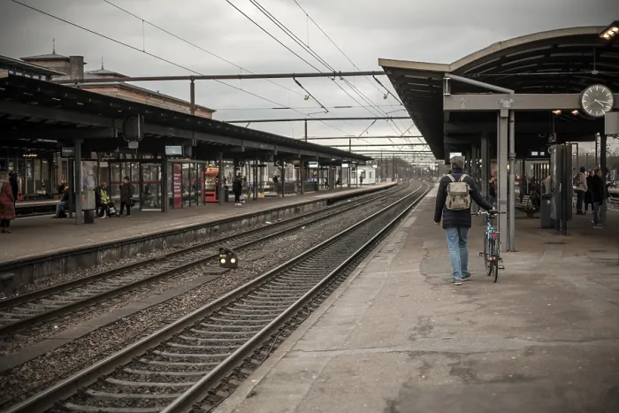 Framed Print : A man walks with a bicycle along a train station platform near railway tracks in Roskilde