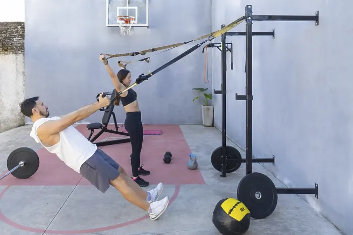 Framed Print : Man and woman engaging in suspension training exercises outdoors in their backyard gym Framed Print : Man and woman engaging in suspension training exercises outdoors in their backyard gym