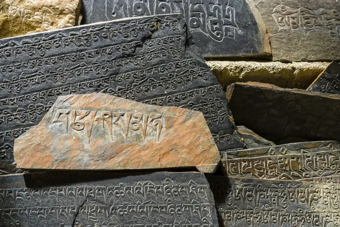Framed Print : Mani stones with the engraved tibetan mantra Om Mani Padme Hum are piled up to a wall