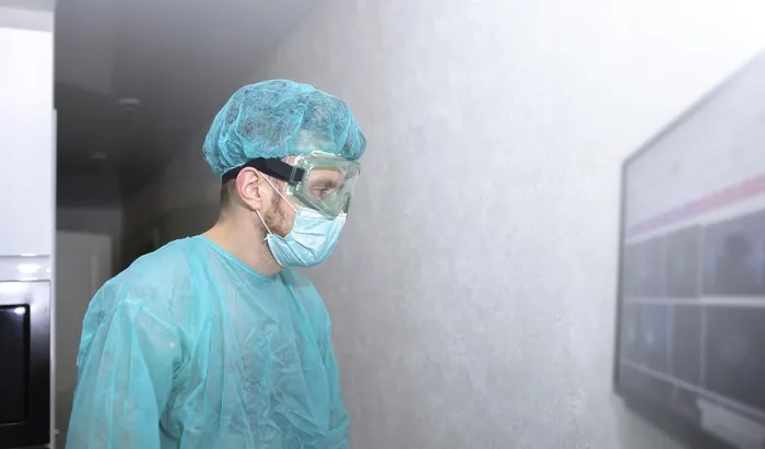 Framed Print : A medical professional in protective gear stands by a wall