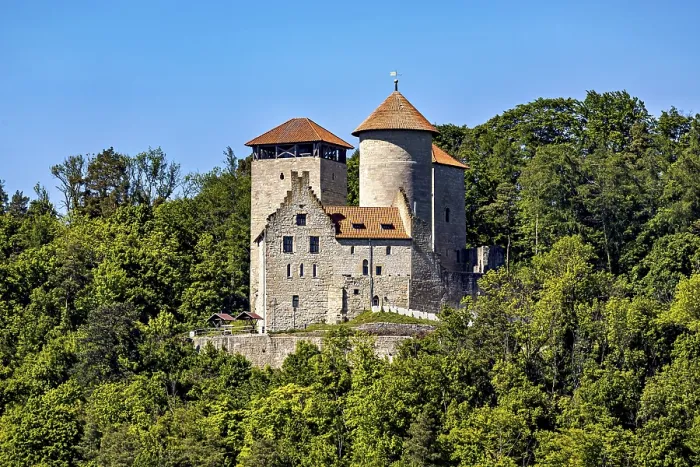 Framed Print : A medieval castle with two towers on a wooded hill under a blue sky