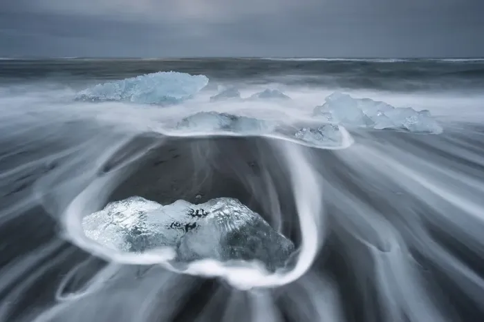 Framed Print : Melting icebergs lying in the strong surf on the black volcanic beach at Joekulsarlon