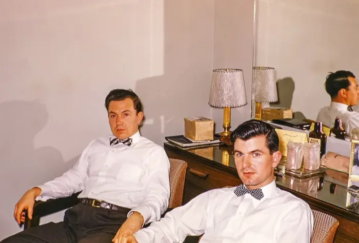 Framed Print : Two men in shirts and bow ties sitting in a hotel room with a mirror in the background, USA around 1953