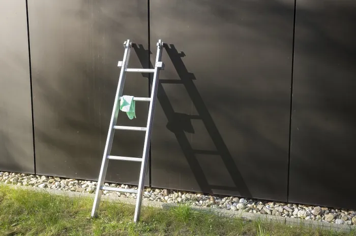 Framed Print : Metal ladder is leaning against a modern building with a cleaning cloth hanging on it
