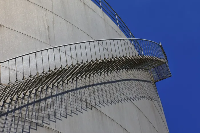 Framed Print : Metal staircase winds around a large tank in an industrial environment