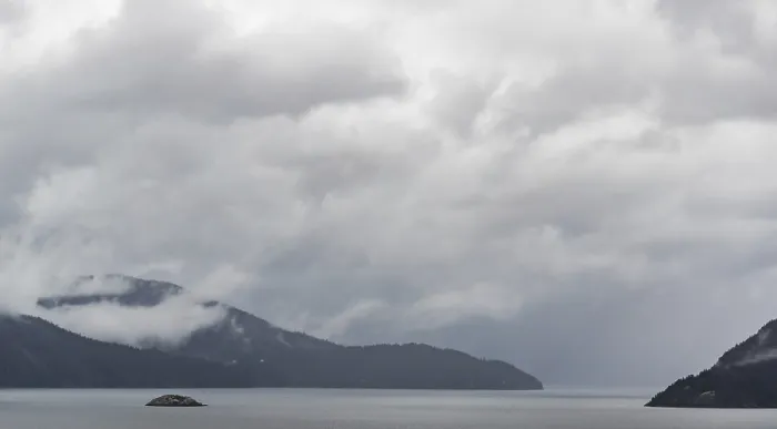 Framed Print : A misty lake with distant mountains and overcast clouds creating a serene