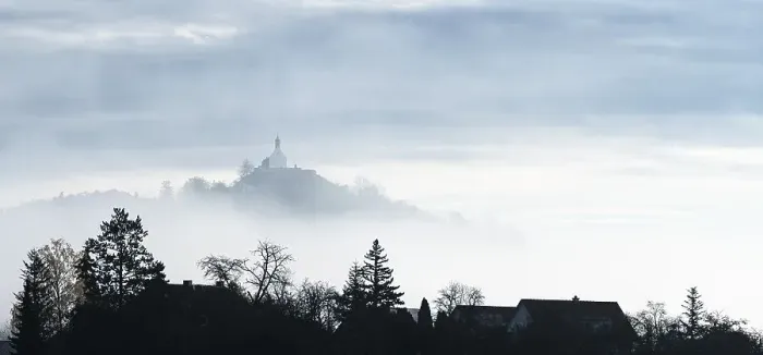 Framed Print : A misty landscape with silhouettes of trees and a chapel on a hill