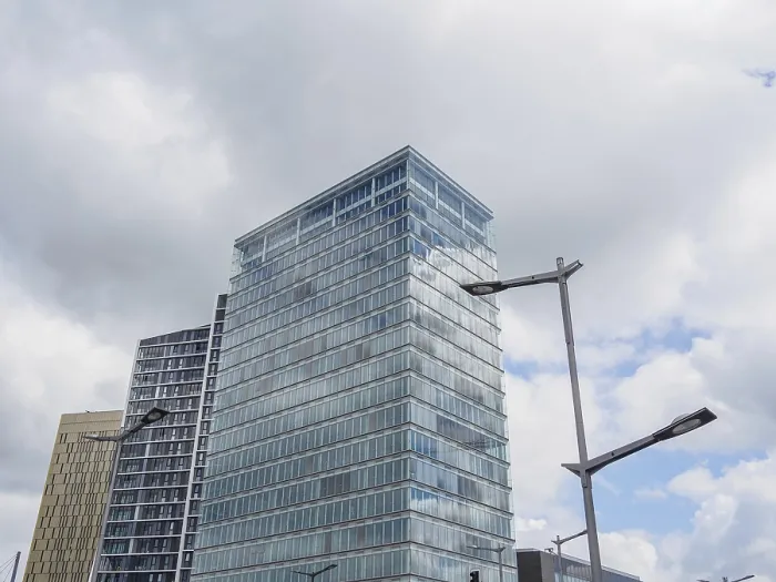 Framed Print : A modern building with a glass facade rises into the cloudy sky Framed Print : A modern building with a glass facade rises into the cloudy sky