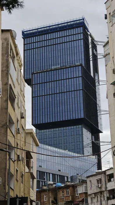 Framed Print : Modern high-rise building with glass facade between older buildings in an urban environment under cloudy sky
