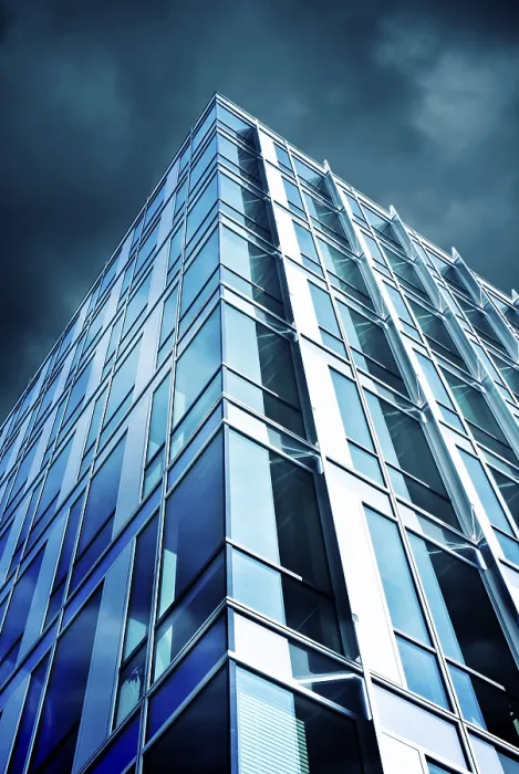 Framed Print : A modern skyscraper with a glass facade reflecting the cloudy sky