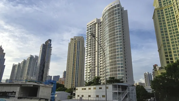 Framed Print : Modern skyscrapers rise into the sky of a city surrounded by trees and clear blue sky