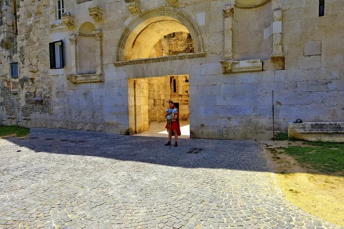 Framed Print : Monumental stone gate with round arch and cobblestones in bright sunshine