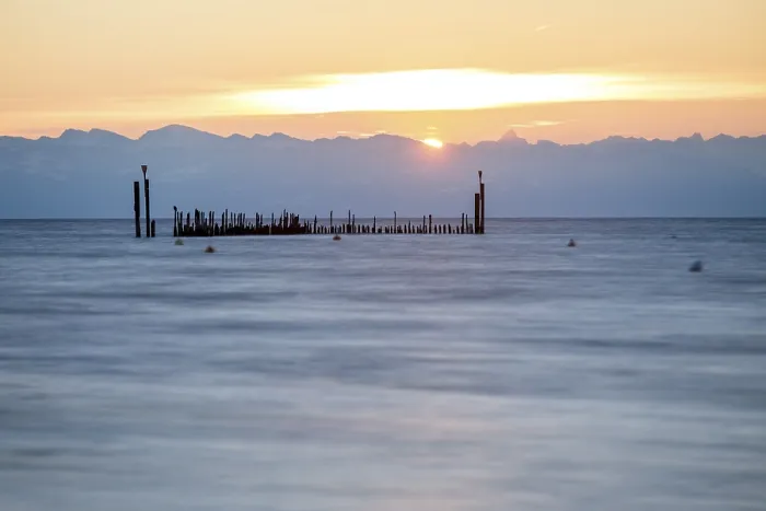 Framed Print : Morning waves under a warm sky with mountain silhouettes