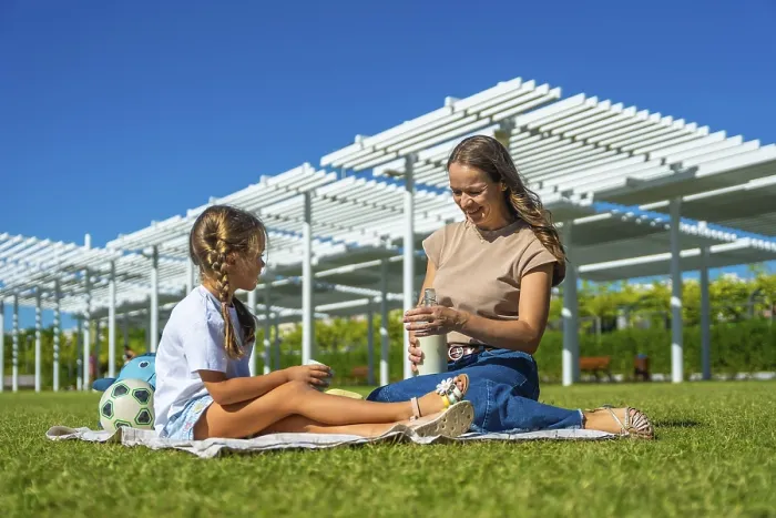 Framed Print : Mother and daughter sitting on a picnic blanket in a sunny urban park