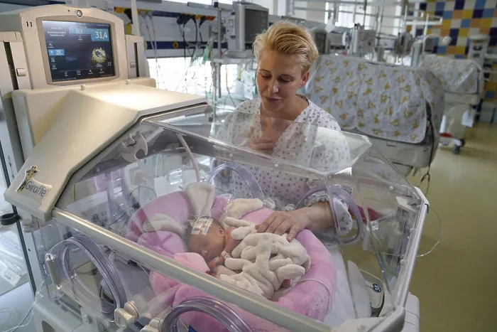 Framed Print : Mother of twins with one of her newborns in an incubator