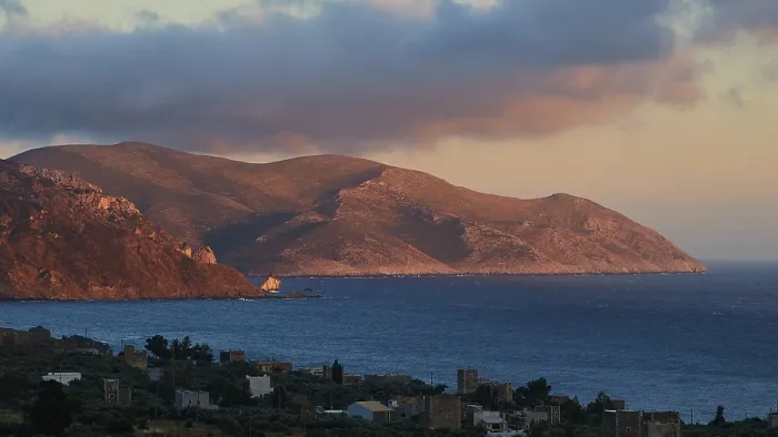 Framed Print : A mountain landscape at dusk with a view of the sea and a small settlement in the foreground