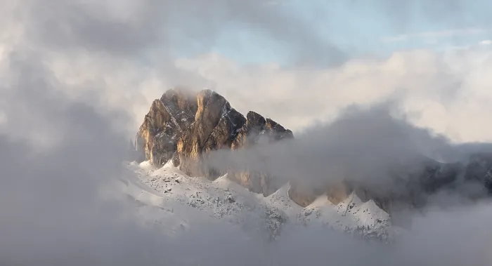 Framed Print : Mountains shrouded in light clouds under a sky flooded with light at the Passo di Falzarego