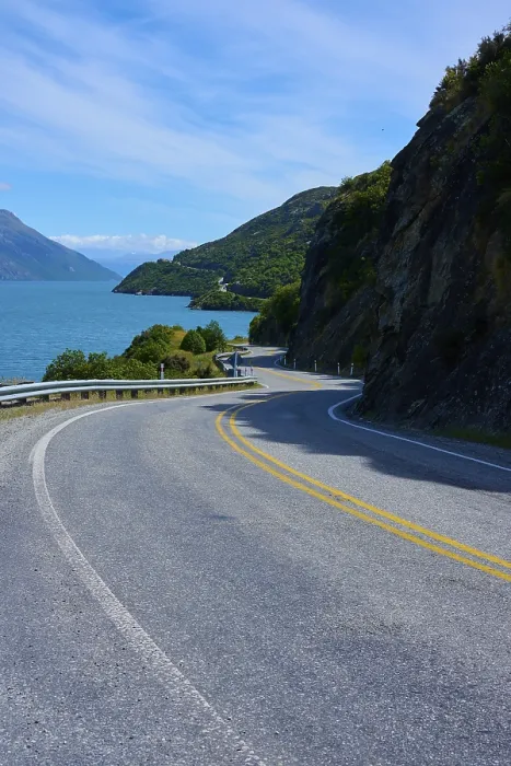 Framed Print : Narrow, winding road meanders along a lake through mountain landscape