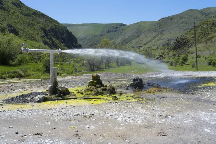Framed Print : Natural spring with sparkling water jet against green mountain landscape under blue sky