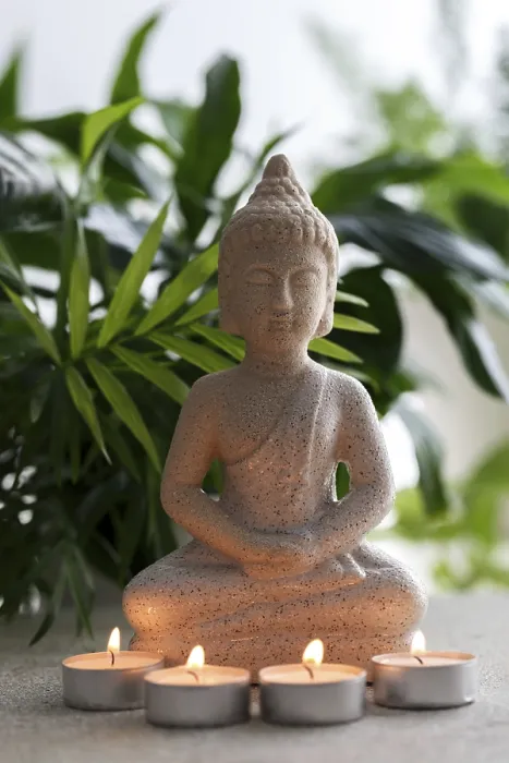 Framed Print : Natural stone statue of Buddha sitting in meditation surrounded by candles and tropical plants Framed Print : Natural stone statue of Buddha sitting in meditation surrounded by candles and tropical plants