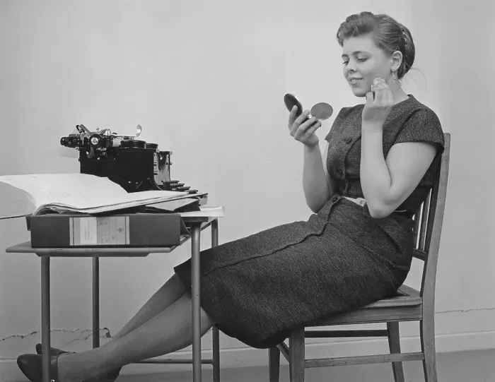 Framed Print : Office girl in the 1950s. A young girl at her typewriter is taking a break from work and is bettering her make up. Sweden 1955