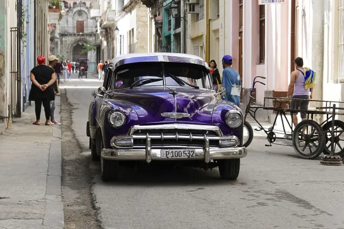 Framed Print : Old classic car parked in a busy street with colonial architecture
