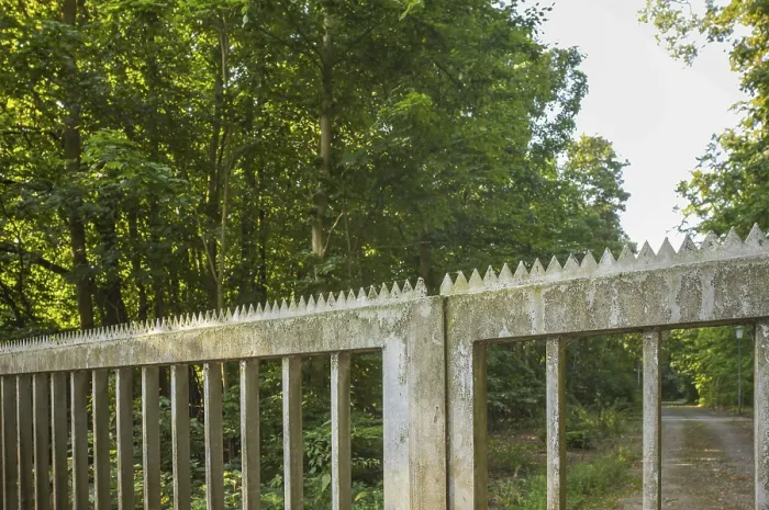 Framed Print : Old concrete fence with sharp metal spikes protecting a restricted forest area