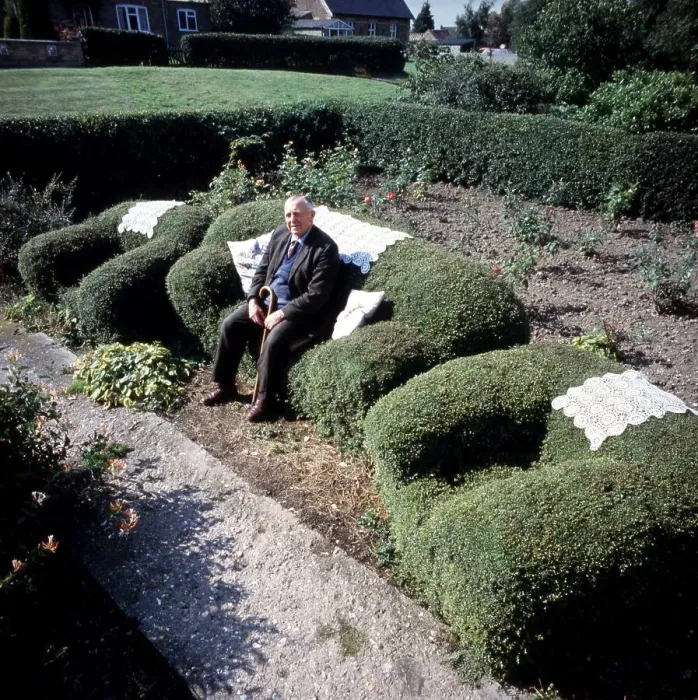 Framed Print : Old man sitting on an armchair cut from a hedge