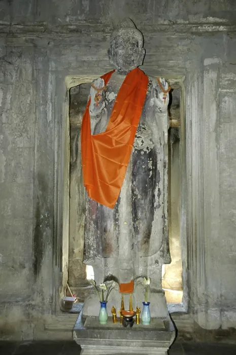 Framed Print : Old statue of a standing Buddha wearing an orange cape