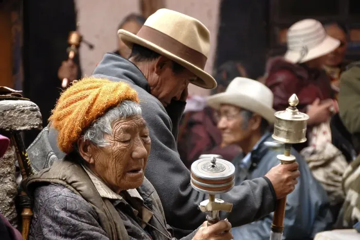 Framed Print : Old Tibetan pilgrims sit in a backyard with prayer wheels Lhasa Tibet China