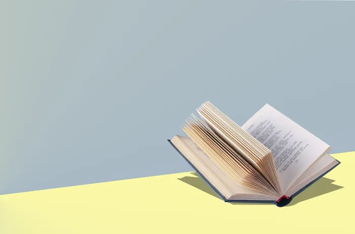 Framed Print : An open book lies on a yellow table
