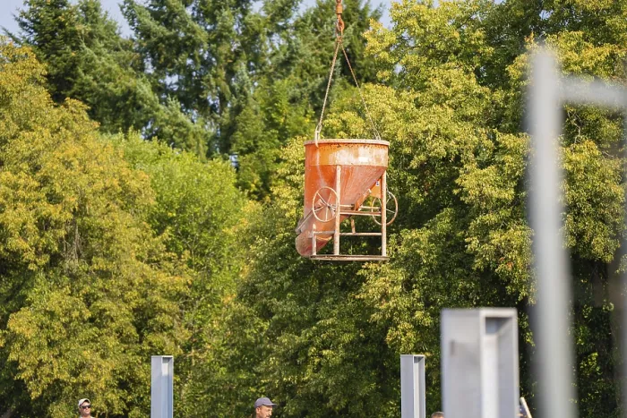 Framed Print : An orange-coloured concrete bucket hovers over a building site
