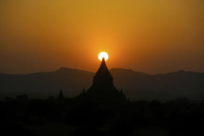 Framed Print : Orange sunset, silhouette with the sun behind the steeple of a Buddhist temple