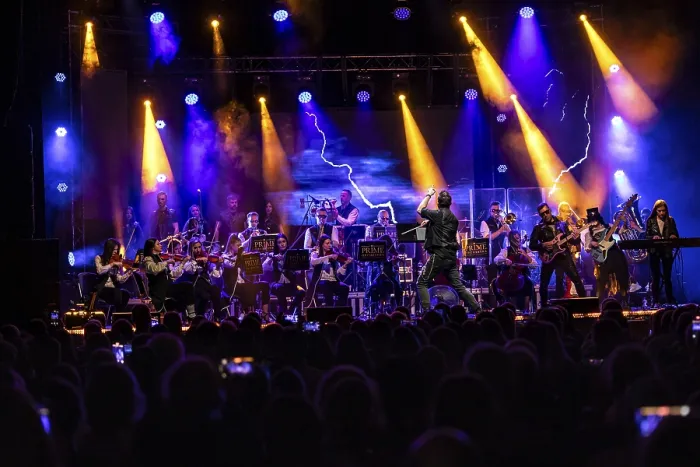 Framed Print : An orchestra plays on an illuminated stage in front of a large audience