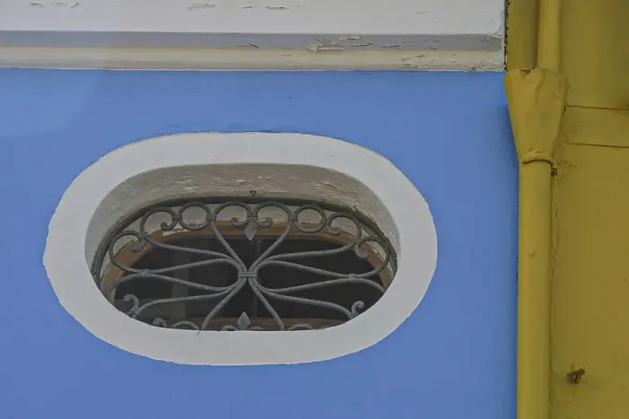 Framed Print : Oval window on blue-yellow house wall Framed Print : Oval window on blue-yellow house wall