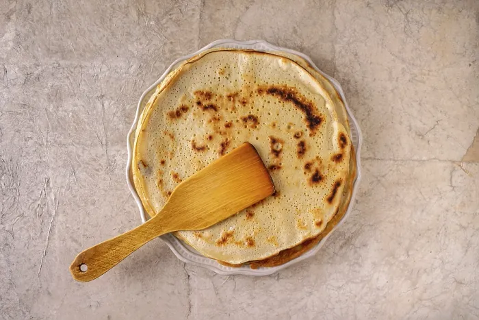 Framed Print : Pancakes and a wooden spatula lie on a round ceramic plate on a beige background