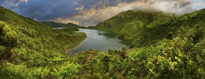 Framed Print : Panoramic view of a lake surrounded by green forested mountains under a dramatic sky Framed Print : Panoramic view of a lake surrounded by green forested mountains under a dramatic sky