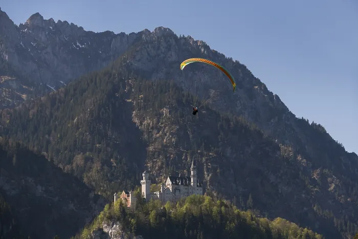 Framed Print : A paraglider flies over the majestic Neuschwanstein Castle in the picturesque mountains