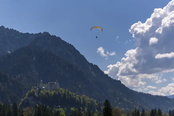 Framed Print : A paraglider over Neuschwanstein Castle with a cloudy sky