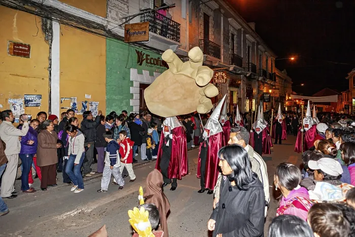 Framed Print : Participants in silver robes carry an oversized hand through the street at night