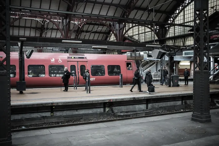 Framed Print : Passengers waiting on a platform beside a red train within a station in Copenhagen Framed Print : Passengers waiting on a platform beside a red train within a station in Copenhagen
